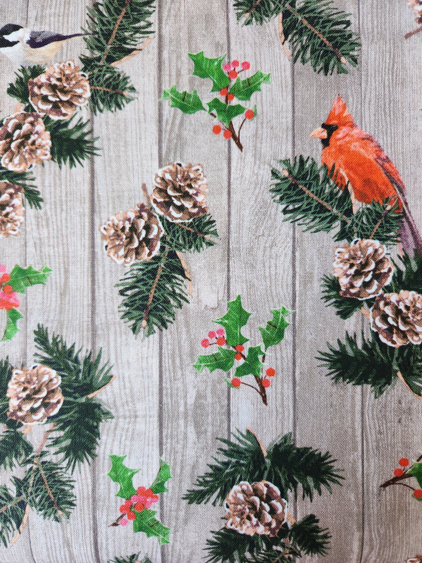 Christmas fabric.  Wood plank background with Cardinals, chickadees, holly, and pinecones